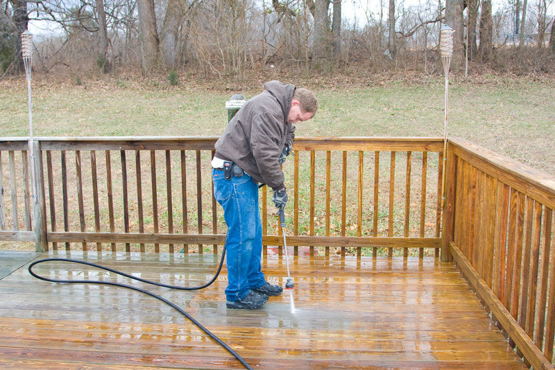 a man using a pressure washer on a deck