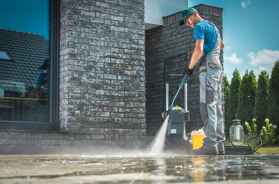 a man using a pressure washer to clean a driveway